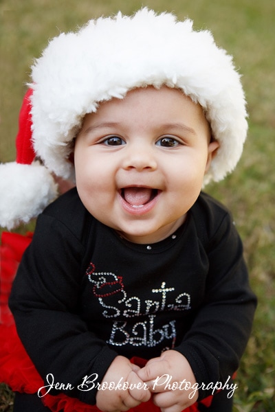A smiling baby wearing a Santa hat captured by Jenn Brookover photography.