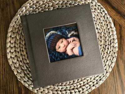 A photo of a baby in a blue hat on a wicker plate.