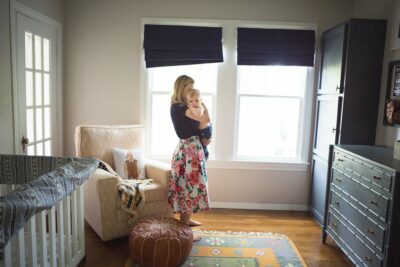 A woman standing in front of a window in a baby's room.