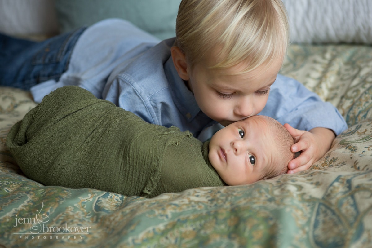 big brother kissing little brother during newborn session at home