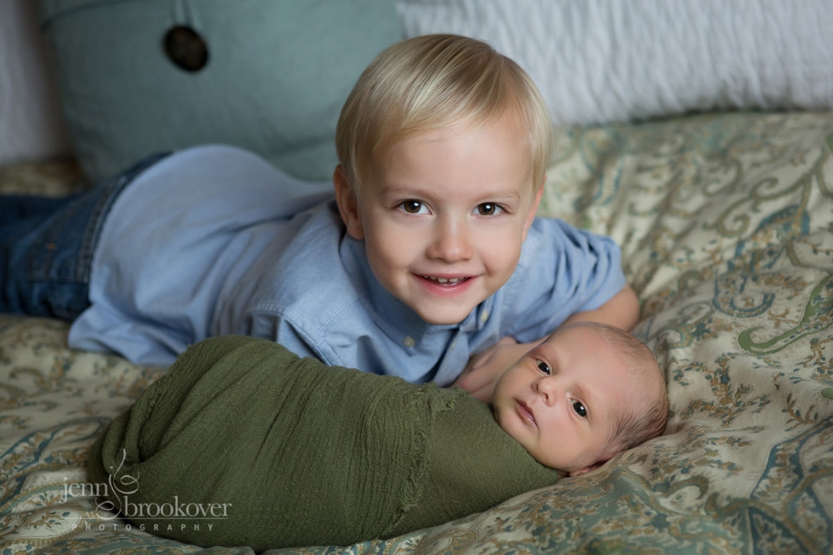 newborn with big brother smiling during photo session at home