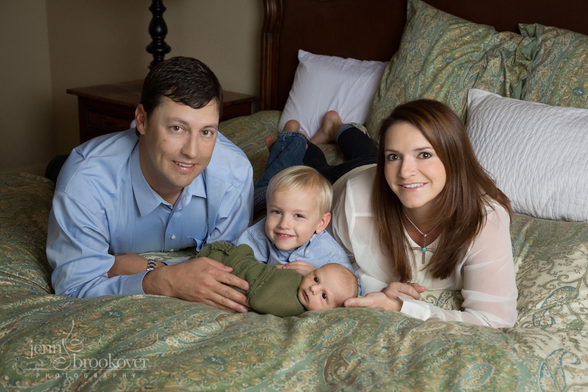 family at home during newborn session smiling on bed