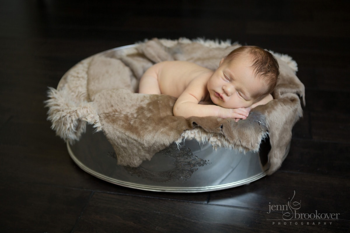 newborn in silver bowl during photo shoot at home, fur