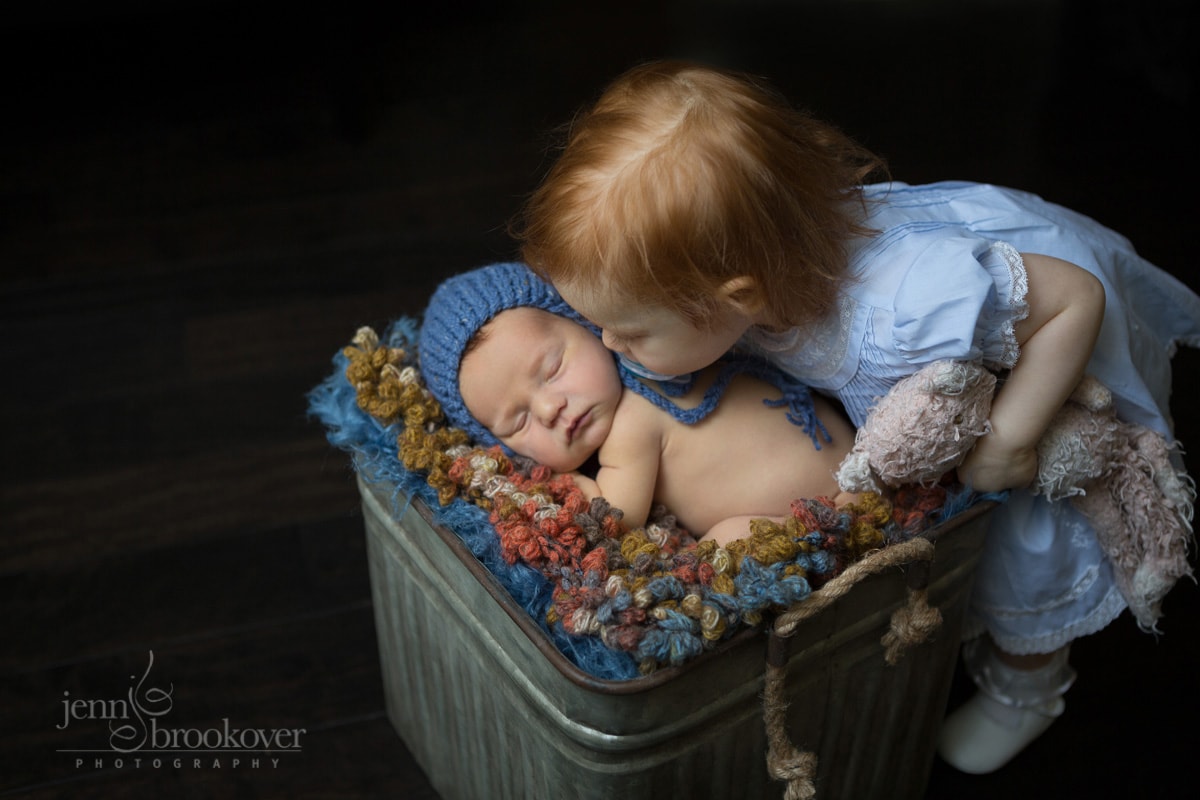 big sister kissing baby brother during newborn photo session
