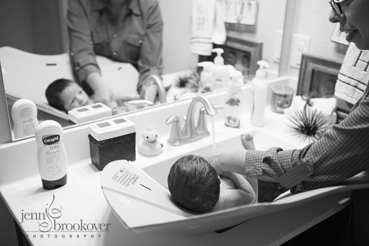 mom giving newborn a bath captured by Jenn Brookover Newborn Photographer San Antonio