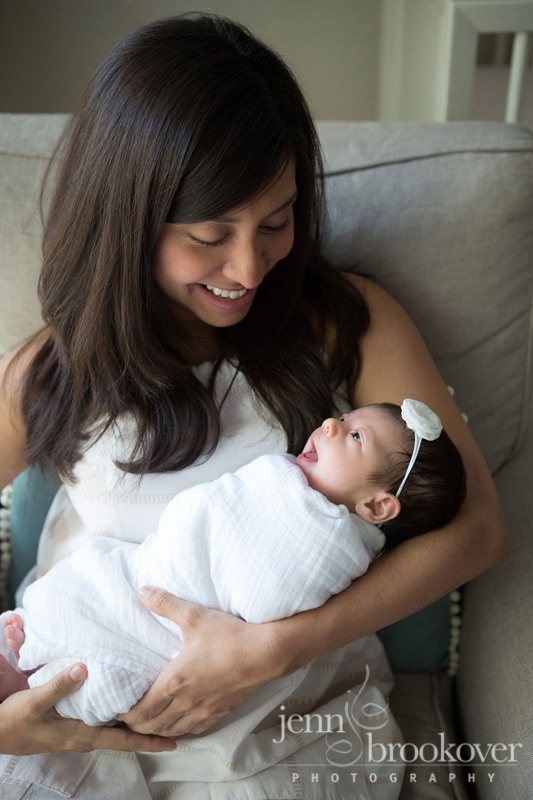 mom holding smiling newborn during lifestyle session at home in San Antonio