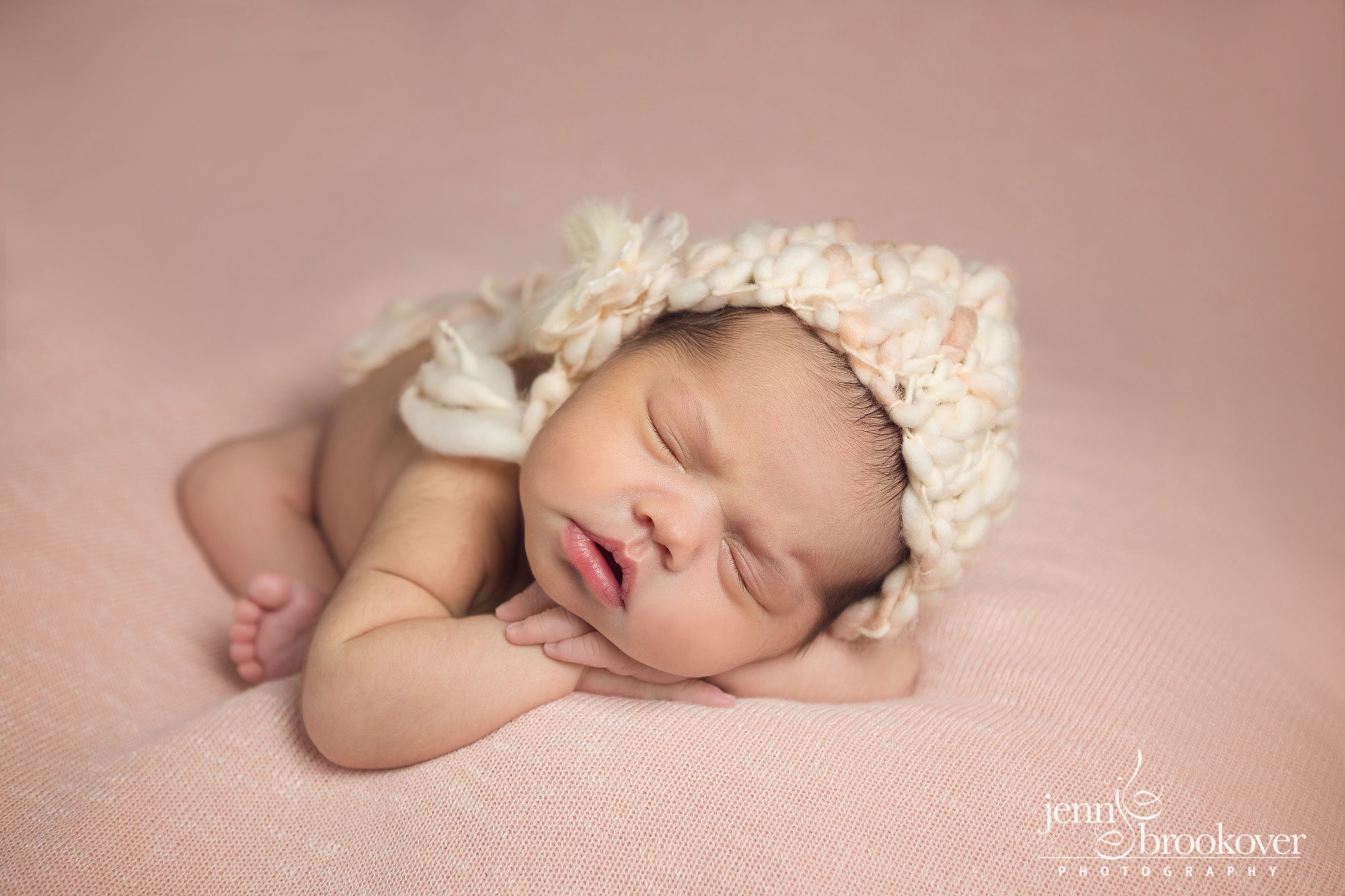 newborn portrait in peach and cream knitted hat, curled up during her session with Jenn Brookover Photography