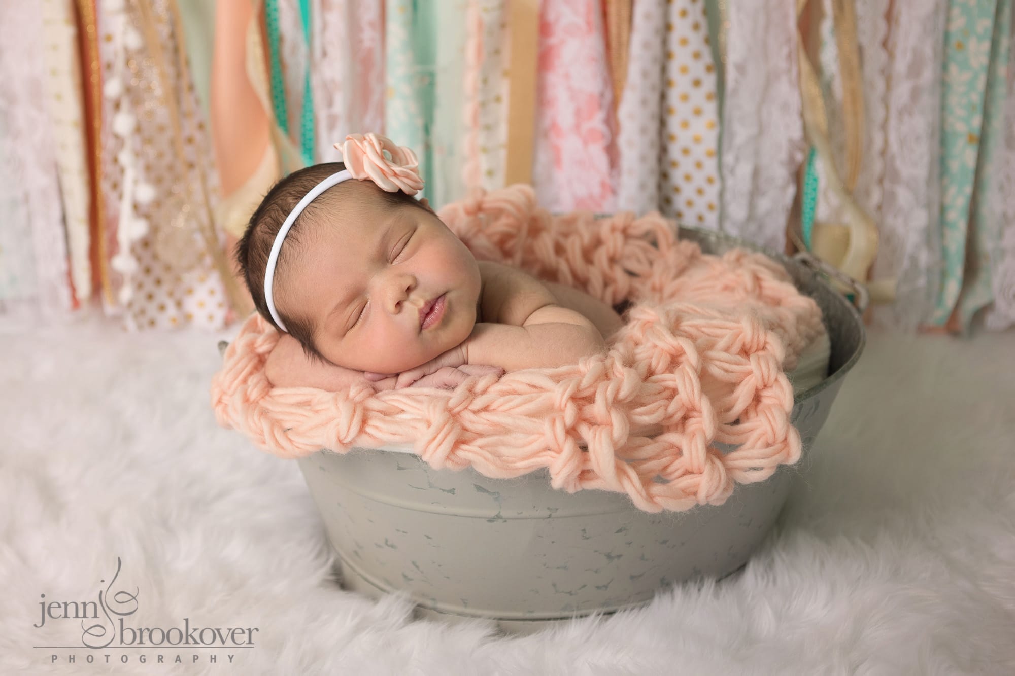 newborn in tin with fabric banner as backdrop taken at home in her nursery in San Antonio by Jenn Brookover