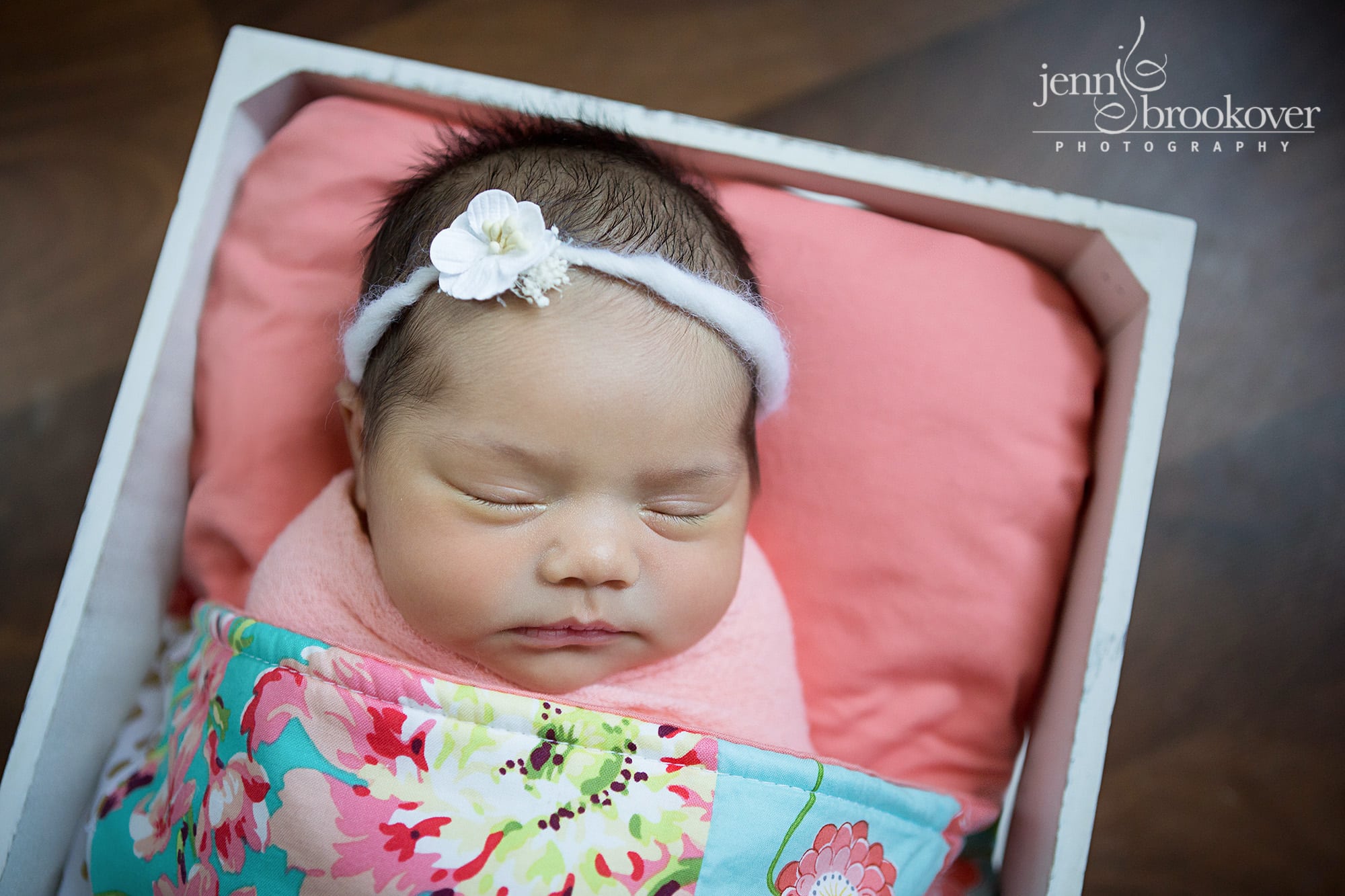 newborn baby girl in a coral, pink and teal quilt and white headband taken by Jenn Brookover in San Antonio