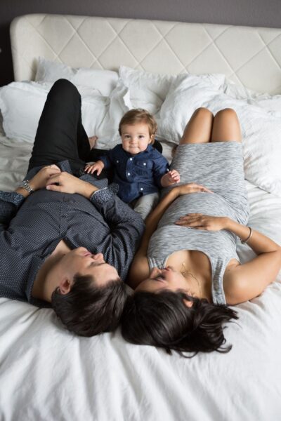A family laying on a bed with a baby on their lap.