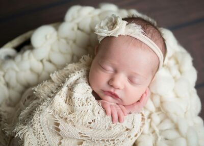 A newborn girl sleeping in a white blanket.
