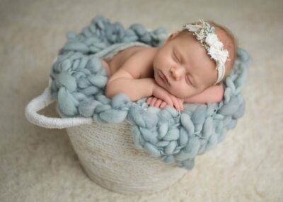 A newborn baby girl sleeping in a basket.