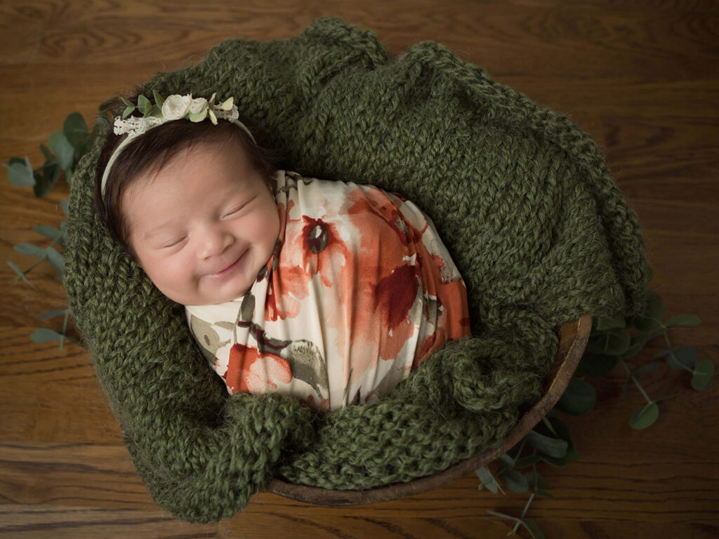 A baby girl in a knitted basket smiling in San Antonio, Texas by Jenn Brookover