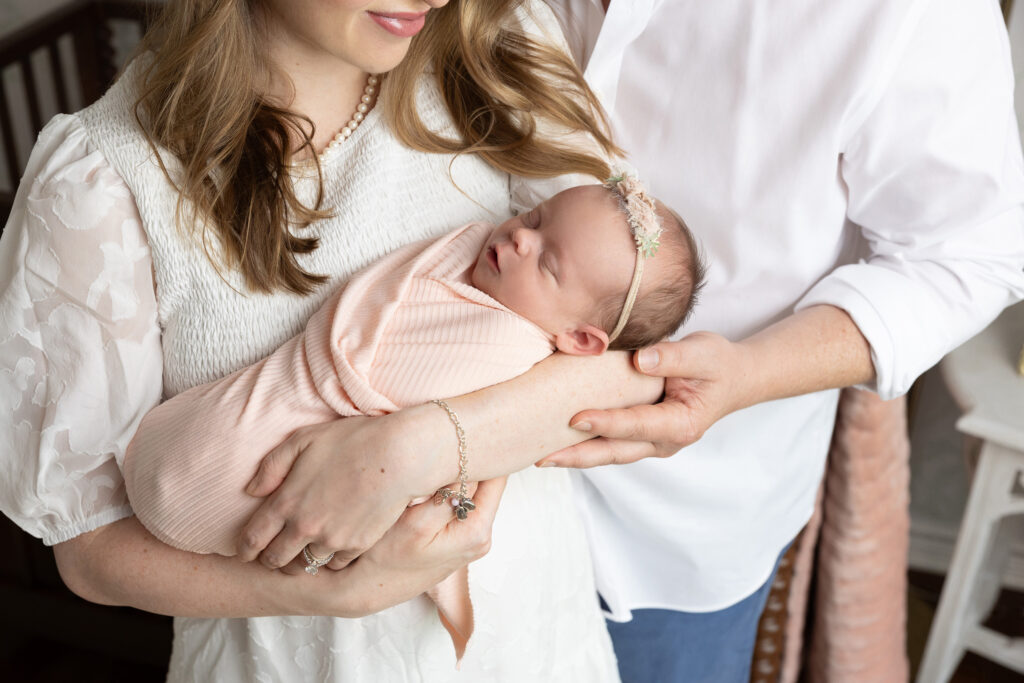 newborn baby girl wrapped in pink with parents in San Antonio, TX during her photo shoot with jenn brookover photography