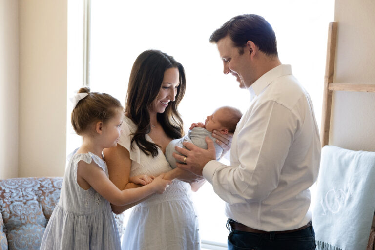 newborn family at home in front of a window during their photo shoot with jenn brookover photography San Antonio, TX